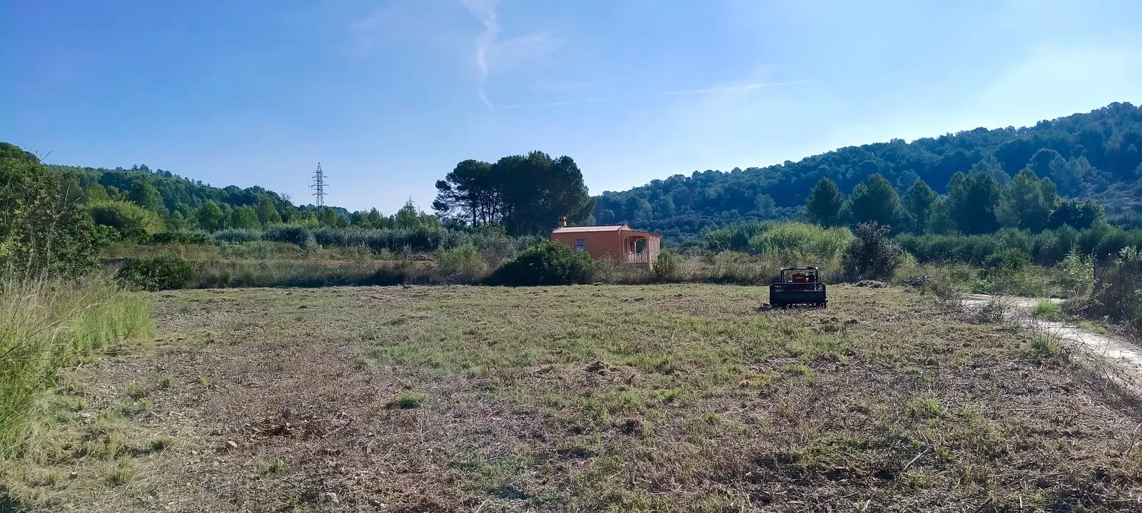 La misma finca desbrozada, con la máquina sobre el terreno